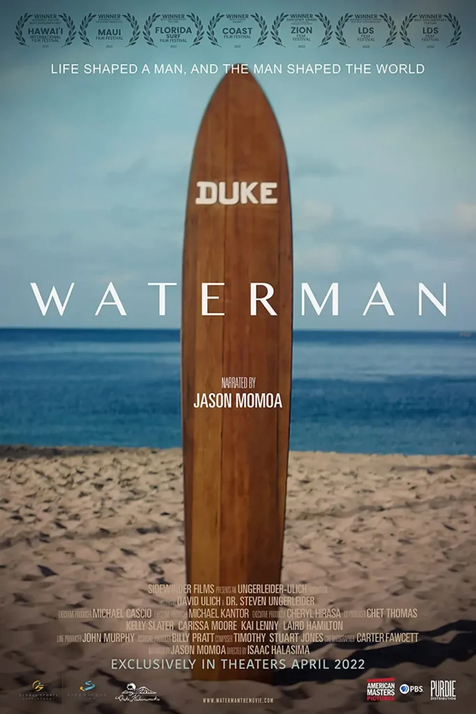 A surfboard on the beach with words " duke waterman ".